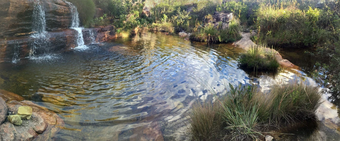 Entardecer na Cachoeira da Sentinela — reflexo dourado na água com paredão ao fundo